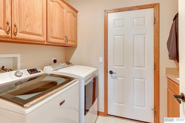 clothes washing area featuring washing machine and clothes dryer and cabinet space