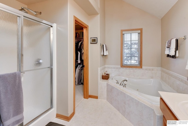 bathroom with a tub with jets, a shower stall, a walk in closet, and vaulted ceiling