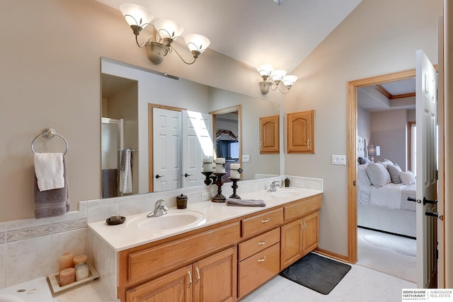 ensuite bathroom featuring lofted ceiling, an inviting chandelier, ensuite bathroom, and a sink