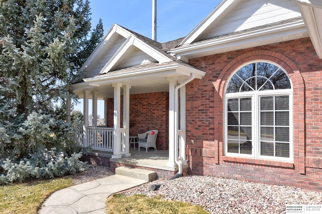 doorway to property featuring brick siding and a porch