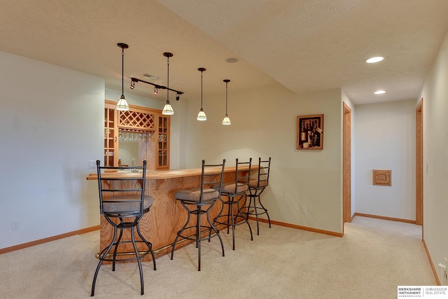 bar with indoor wet bar, light carpet, and baseboards