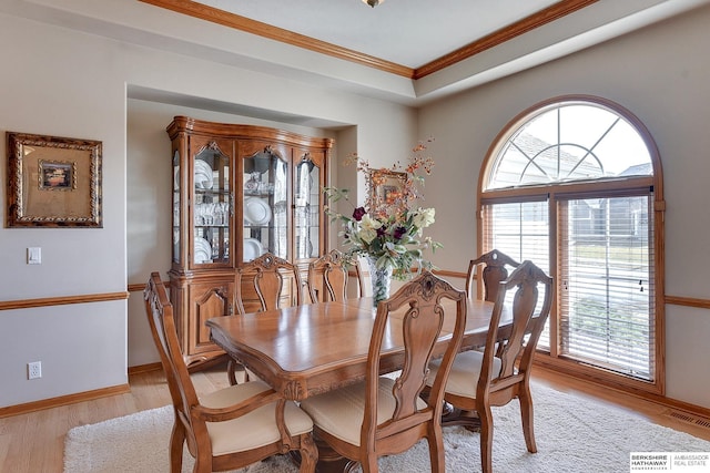 dining room with visible vents, light wood-style flooring, baseboards, and ornamental molding