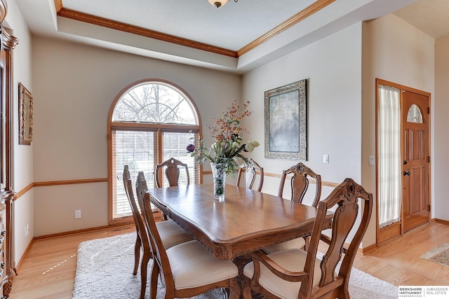 dining area with a tray ceiling, baseboards, light wood-type flooring, and ornamental molding