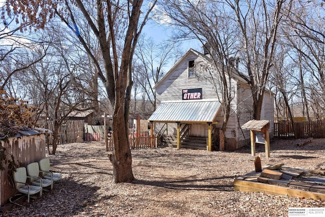 back of property with metal roof and fence