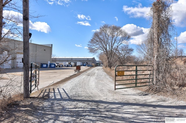 view of street featuring a gated entry, dirt driveway, and a gate
