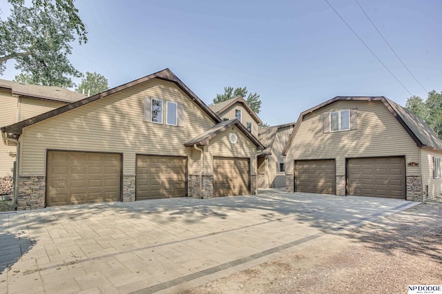 view of front of home featuring stone siding, a gambrel roof, and driveway