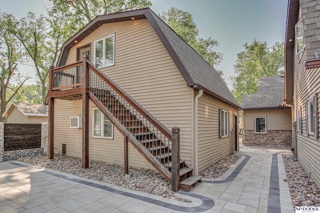 view of home's exterior with a patio area, a gambrel roof, a shingled roof, and stairs