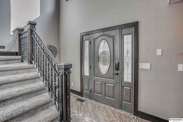 entryway with stairway, baseboards, and wood finished floors