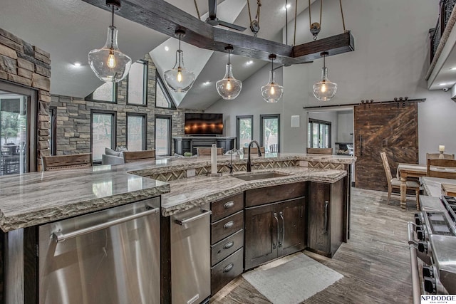 kitchen featuring a sink, stainless steel appliances, dark brown cabinets, a barn door, and open floor plan