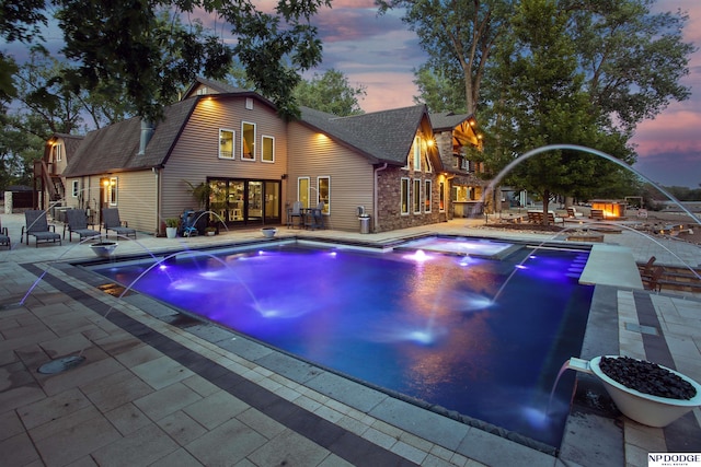 outdoor pool with a patio area and a hot tub