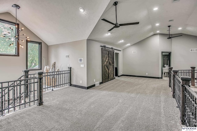 interior space featuring visible vents, baseboards, a barn door, and vaulted ceiling