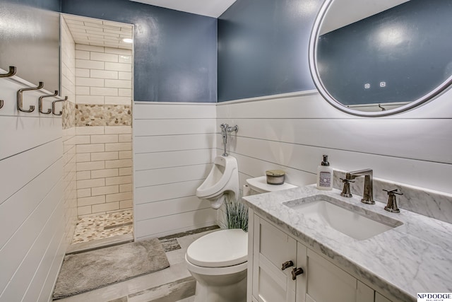 full bath with a wainscoted wall, tiled shower, toilet, and vanity