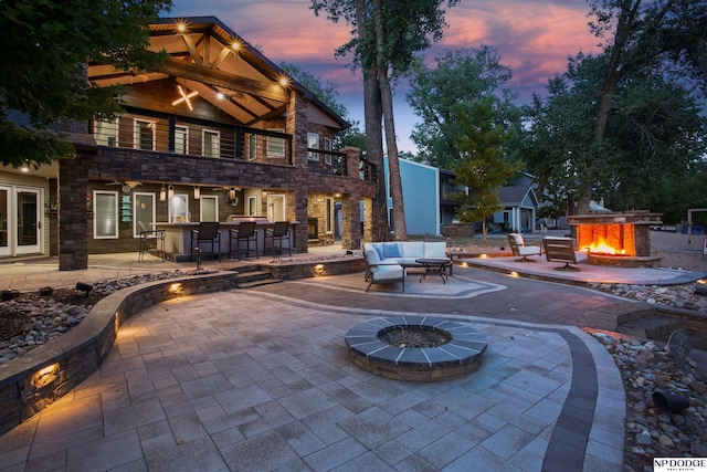 patio terrace at dusk featuring an outdoor living space with a fire pit and outdoor dry bar