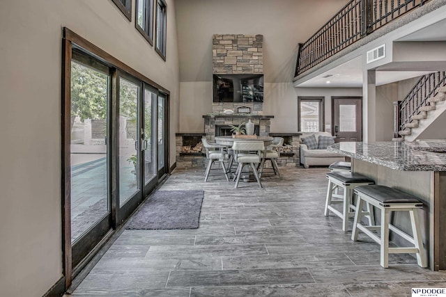 dining room featuring stairway, a high ceiling, visible vents, and wood finished floors