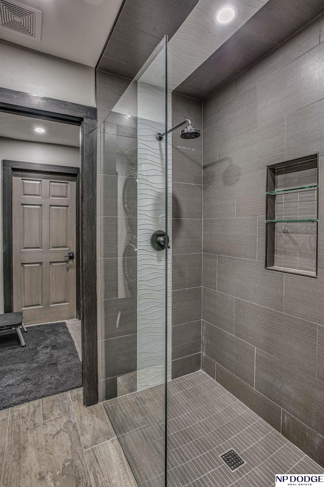 bathroom featuring wood finish floors, visible vents, and walk in shower