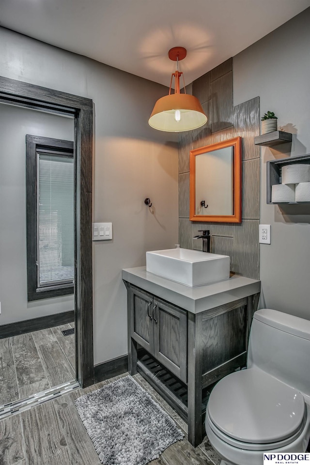 bathroom featuring baseboards, toilet, vanity, and wood finish floors