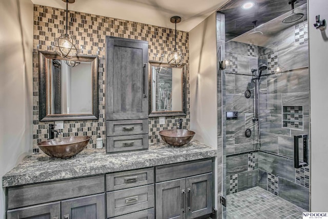 bathroom featuring double vanity, decorative backsplash, a shower stall, and a sink