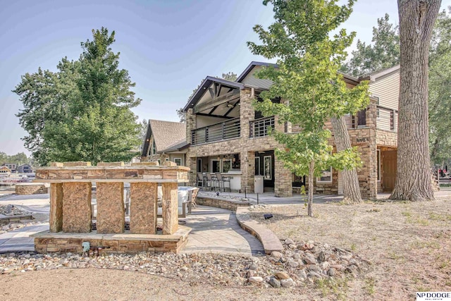 view of front facade with stone siding, ceiling fan, and a patio