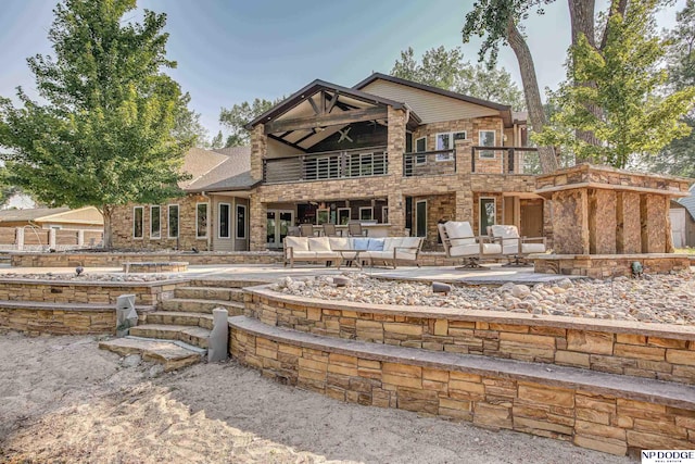 rear view of house featuring an outdoor living space, a patio, and stone siding