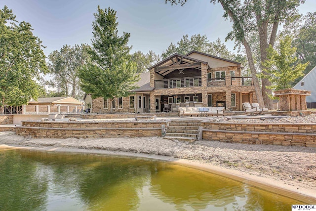 rear view of house with an outdoor hangout area, a balcony, a patio, and a water view