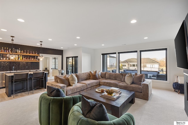 living area featuring wet bar, recessed lighting, light colored carpet, and a fireplace