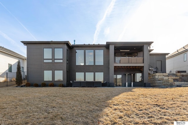 rear view of property with a balcony, a yard, and fence