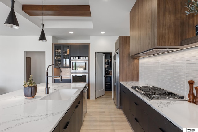 kitchen featuring a sink, glass insert cabinets, appliances with stainless steel finishes, modern cabinets, and backsplash