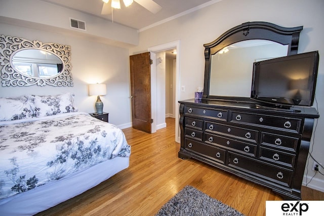 bedroom with visible vents, baseboards, ornamental molding, light wood-style floors, and a ceiling fan