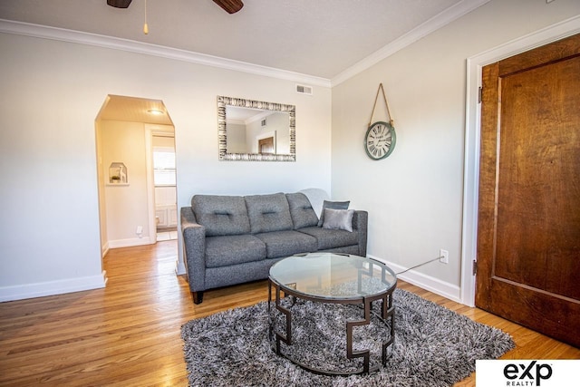 living room featuring visible vents, baseboards, wood finished floors, and ornamental molding