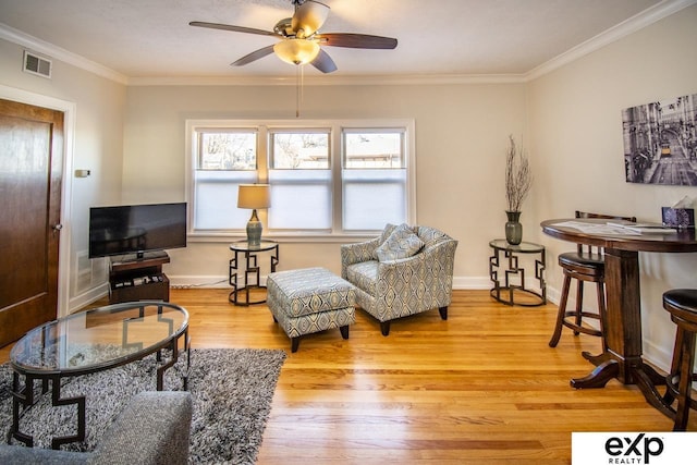 living area featuring visible vents, baseboards, wood finished floors, and ornamental molding