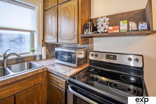 kitchen with a sink, light countertops, brown cabinetry, and stainless steel appliances