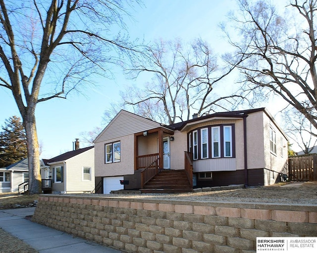 view of front of property featuring stucco siding, an attached garage, and fence