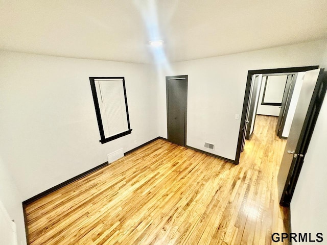 spare room featuring baseboards, visible vents, and light wood finished floors