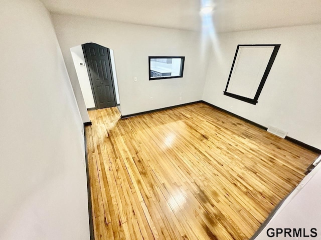 spare room with visible vents, light wood-type flooring, and baseboards