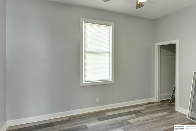 unfurnished bedroom featuring wood finished floors, baseboards, a closet, and ceiling fan