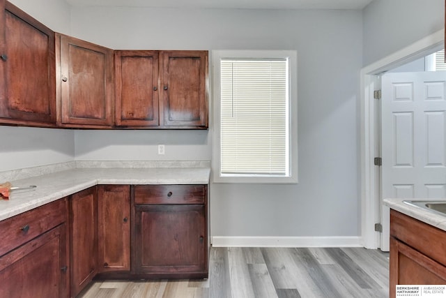 kitchen with baseboards, light wood-style floors, and light countertops