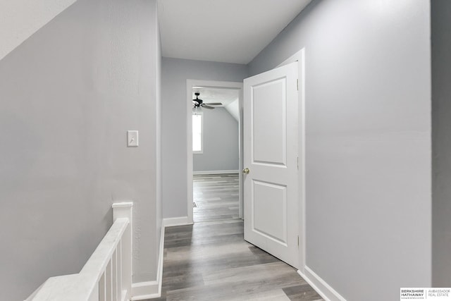 hallway featuring light wood-style flooring, an upstairs landing, and baseboards