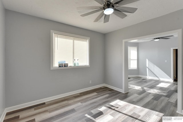 unfurnished room featuring wood finished floors, baseboards, and ceiling fan