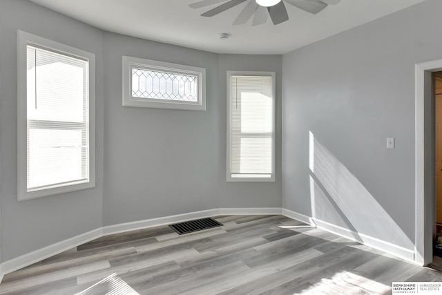 empty room featuring wood finished floors, baseboards, visible vents, and ceiling fan