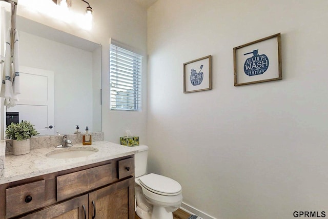 half bath featuring toilet, vanity, and baseboards