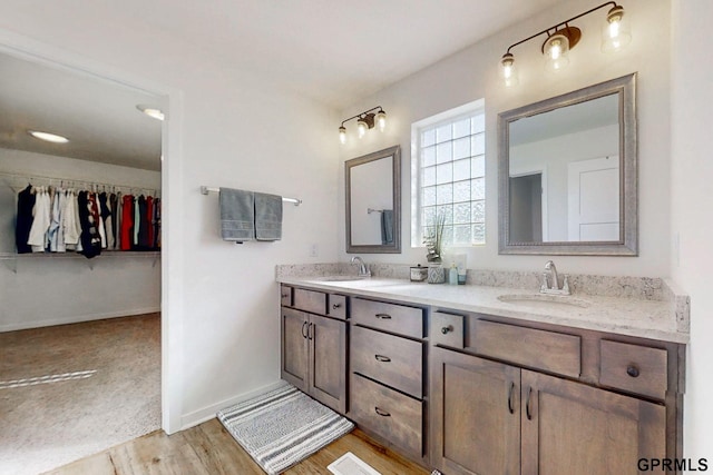 full bath featuring double vanity, wood finished floors, baseboards, and a sink