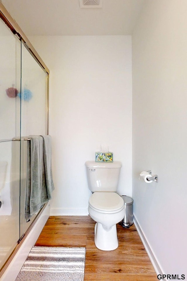 bathroom with a shower with shower door, baseboards, toilet, and wood finished floors