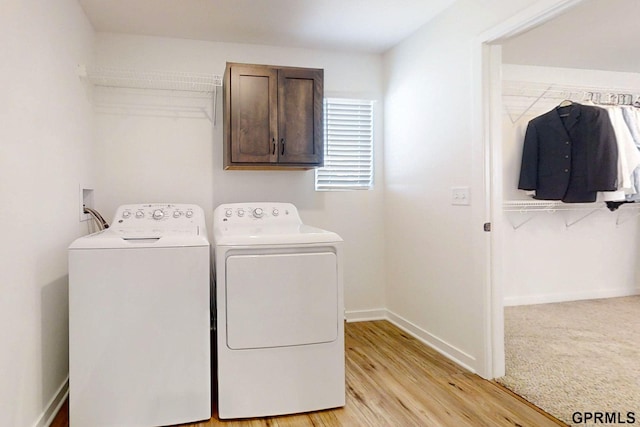 washroom with light wood-style flooring, cabinet space, independent washer and dryer, and baseboards