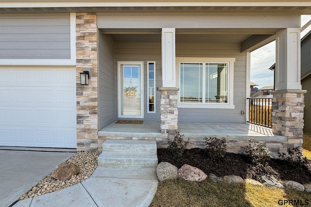 doorway to property with stone siding, a porch, and a garage