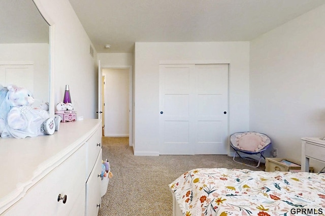 bedroom with a closet, light carpet, and baseboards