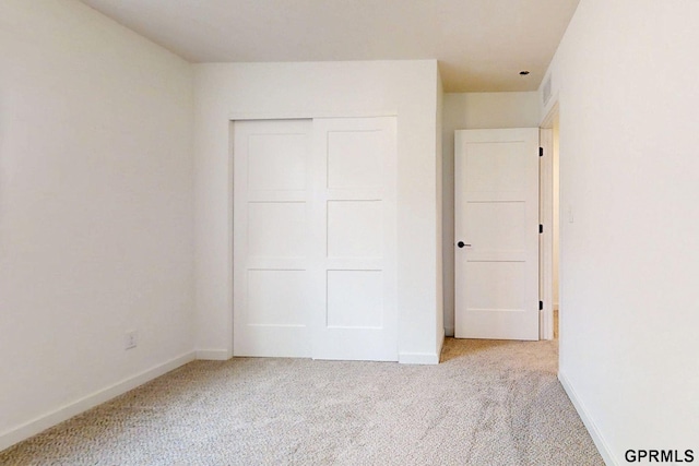 unfurnished bedroom featuring a closet, carpet flooring, visible vents, and baseboards