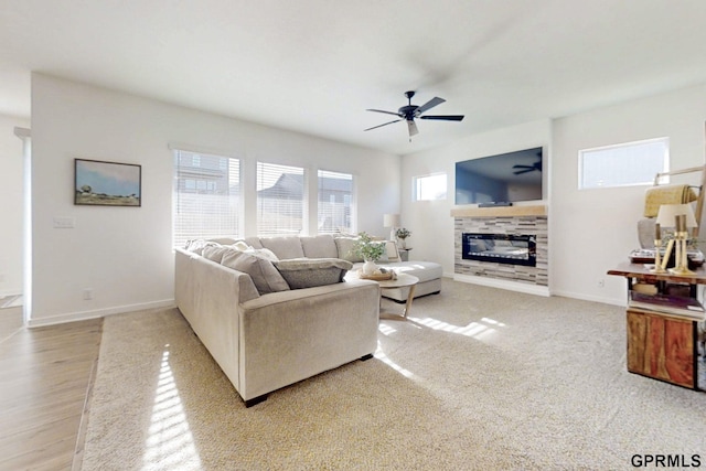 living room with baseboards, ceiling fan, and a tiled fireplace