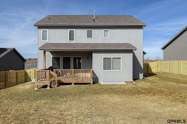 rear view of house with roof with shingles, a lawn, a fenced backyard, and a wooden deck