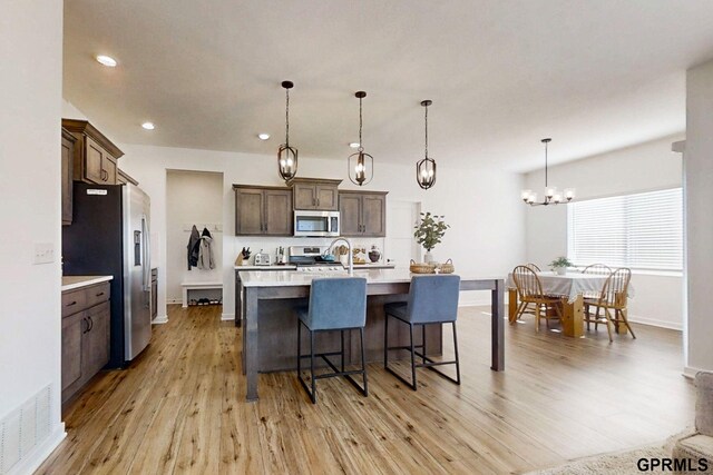 kitchen featuring a breakfast bar, appliances with stainless steel finishes, light wood-style flooring, and light countertops