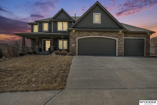 craftsman-style house featuring concrete driveway, covered porch, a garage, and a front lawn